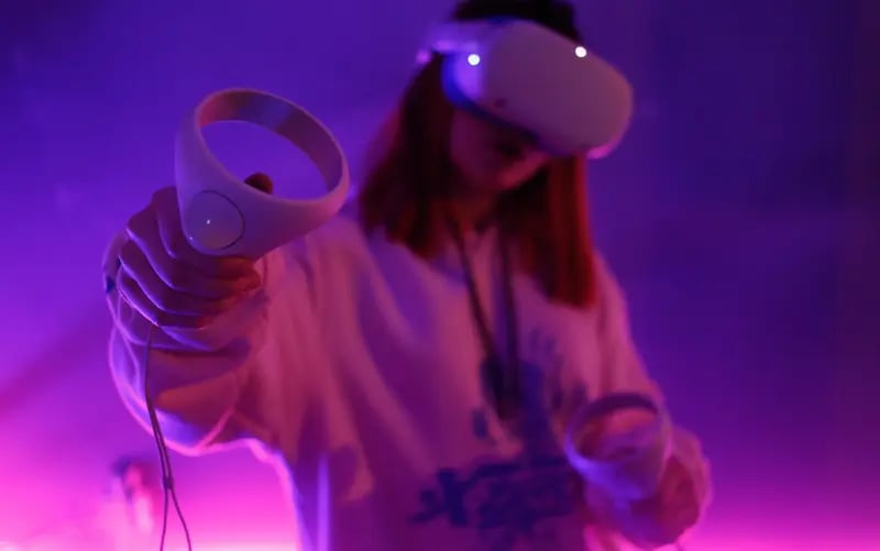 A young girl is standing in the living room with her virtual reality goggles on to get into the Metaverse and catch up on the latest news.