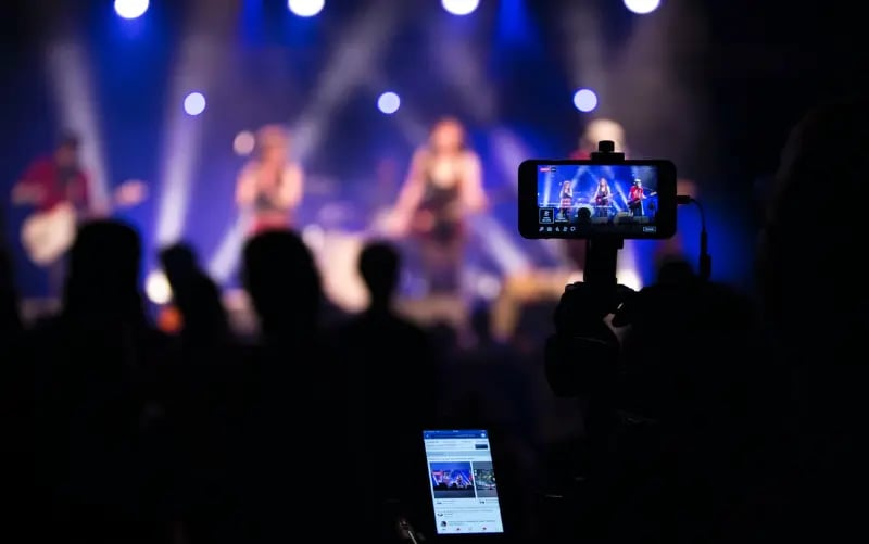 Fans in einer Menschenmenge, die ein Konzert mit ihren mobilen Geräten filmen