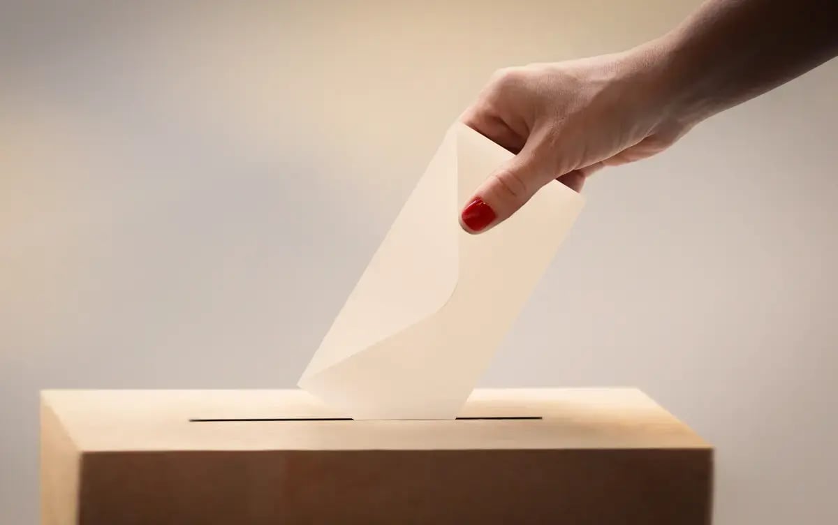 Illustration of a hand placing a ballot into a box - highlighting that elections are an ideal topic for live blog coverage.