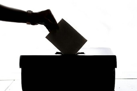 A voter casting their vote in a ballot box.